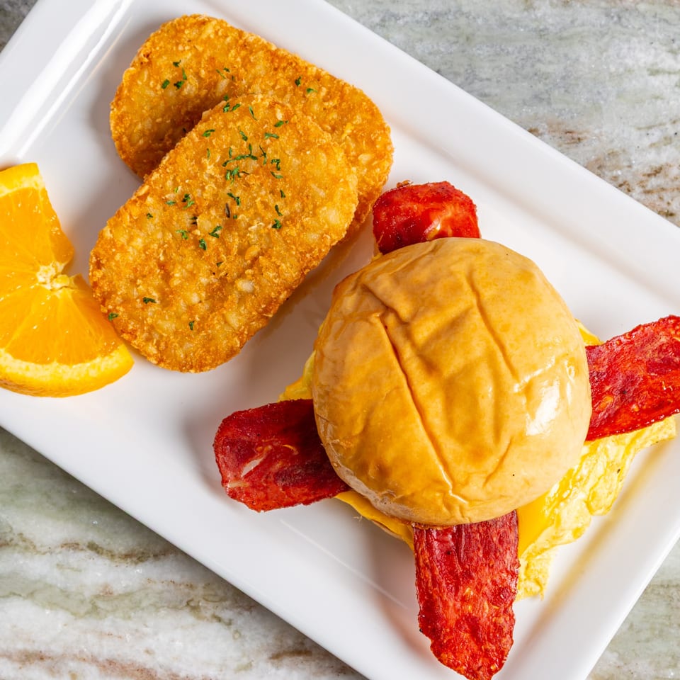 Big John's Eatery breakfast with hash browns, orange slice, and a breakfast sandwich.
